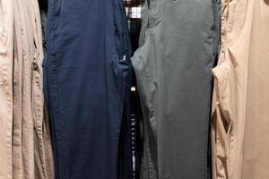 messa a fuoco selettiva, moda, concetto di abbigliamento, vestiti o pantaloni molti colori sono appesi su uno scaffale in un negozio di abbigliamento firmato. un sacco di colori pastello foto