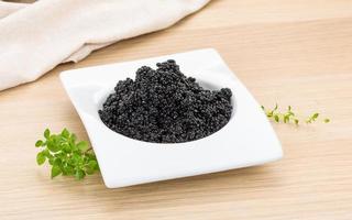 caviale nero in una ciotola su fondo di legno foto