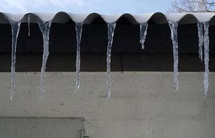 ghiaccioli sospeso a partire dal un' tetto di un' fienile foto