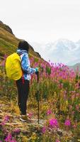 giovane donna felice in forma stare sul punto di vista dopo aver raggiunto la cima in montagna. donna turistica spensierata guardando il sole che si gode il paesaggio. ragazza viaggiatore in cima alla montagna nei raggi del tramonto foto