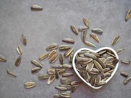 girasole semi nel un' bianca a forma di cuore tazza foto