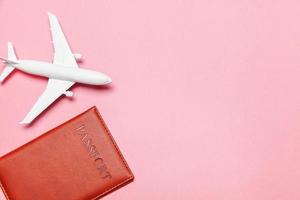 minimo semplice piatto posare viaggio avventura viaggio concetto con aereo e passaporto su rosa pastello di moda moderno sfondo foto
