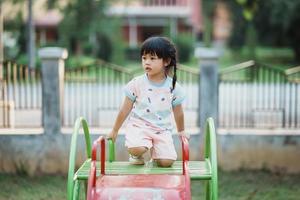 carino asiatico ragazza Sorridi giocare su scuola o scuola materna cortile o terreno di gioco. salutare estate attività per bambini. poco asiatico ragazza arrampicata all'aperto a terreno di gioco. bambino giocando su all'aperto terreno di gioco. foto