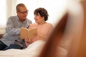 contento asiatico coppie lettura un' libro insieme nel il Casa. foto