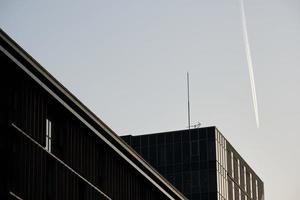 scia di condensazione nel leggero blu cielo al di sopra di moderno edifici foto