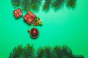 superiore Visualizza di Natale regalo scatola rosso palle con abete rosso rami e campana su verde sfondo. foto