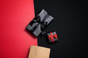 superiore Visualizza di nero regalo scatola con rosso e nero nastri isolato su nero sfondo. foto