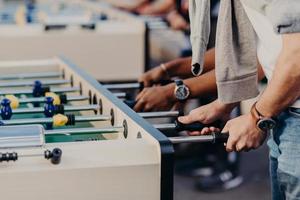 concetto di persone, stile di vita, gioco d'azzardo e ricreazione. il giocatore maschio attivo si gode il tempo libero mentre gioca a calcio balilla insieme. le persone hanno una partita di kicker foto