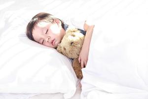 poco asiatico ragazza addormentato con sua giocattolo orsacchiotto orso foto