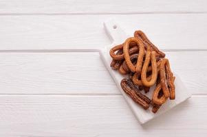 churros fatti in casa su uno sfondo di legno bianco. foto