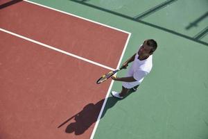 il giovane gioca a tennis all'aperto foto