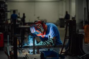 saldatore professionista dell'industria pesante che lavora all'interno della fabbrica, indossa il casco e inizia a saldare. messa a fuoco selettiva foto