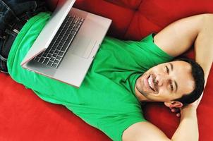 uomo rilassante su divano e opera su il computer portatile calcolatore rilassante su foto