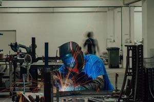 saldatore professionista dell'industria pesante che lavora all'interno della fabbrica, indossa il casco e inizia a saldare. messa a fuoco selettiva foto