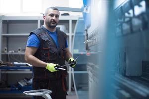 un operaio o un ingegnere intelligente realizza macchine in un'officina di produzione. il concetto di industria e ingegneria. messa a fuoco selettiva foto