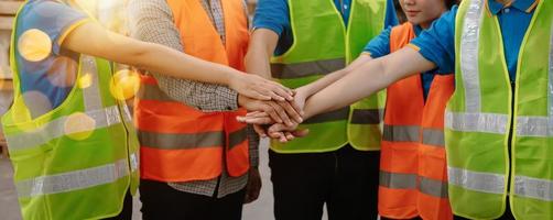 felicità ingegnere e lavoratore squadra gruppo unendo mani a carico contenitori. nel sole lignt foto