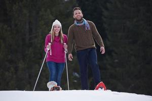 coppia divertendosi e camminando con le racchette da neve foto