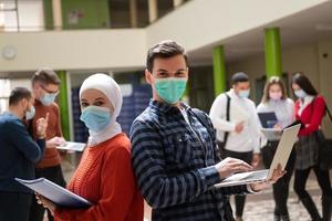 ritratto di multietnico studenti gruppo a Università indossare protettivo viso maschera foto