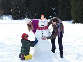 famiglia felice che fa pupazzo di neve foto
