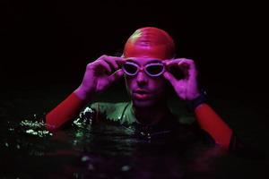 autentico triatleta nuotatore avendo un' rompere durante difficile formazione su notte neon gel leggero foto