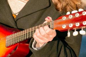 un' giovane uomo giochi il mandolino nel il città su il strada. avvicinamento mani foto