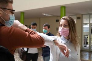 studenti saluto nuovo normale coronavirus stretta di mano e gomito urtando foto