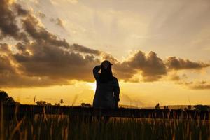 il indietro ombra di un' donna seduta su un' di legno ponte nel il leggero di il sera sole. foto