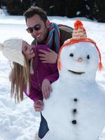 ritratto di contento giovane coppia con pupazzo di neve foto