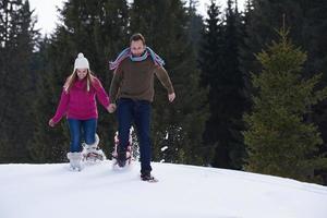 coppia divertendosi e camminando con le racchette da neve foto
