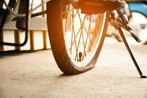 avvicinamento Visualizza di posteriore piatto pneumatico di Vintage ▾ bicicletta quale parcheggiata su marciapiede accanto il strada. morbido e selettivo messa a fuoco. foto