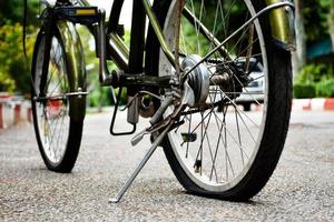 avvicinamento Visualizza di posteriore ruota di vecchio bicicletta quale è piatto e parcheggiata su marciapiede nel il pubblico parco, morbido e selettivo messa a fuoco. foto