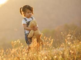 triste poco ragazza sensazione solo nel il parco concetto. solitario bellissimo bambino piccolo ragazza restare solo nel il parco. a tramonto con bagliore foto