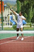 il giovane gioca a tennis all'aperto foto