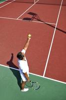 il giovane gioca a tennis all'aperto foto