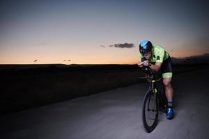 atleta di triathlon in bicicletta veloce di notte foto