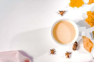 composizione autunnale. tazza di caffè, foglie autunnali, bastoncini di cannella e stelle di anice su sfondo blu pastello brillante. spazio di copia piatto e vista dall'alto. foto