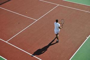 il giovane gioca a tennis all'aperto foto