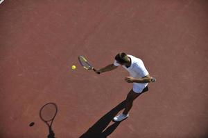 il giovane gioca a tennis all'aperto foto