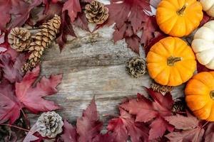 arredamento festivo autunnale da zucche, pini e foglie su uno sfondo di legno. concetto di giorno del ringraziamento o halloween. composizione autunnale piatta con spazio di copia. foto