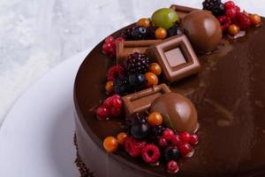 un' avvicinamento tiro di un' cioccolato Smalto torta decorato con frutti di bosco. foto