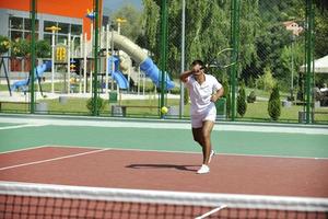 il giovane gioca a tennis all'aperto foto