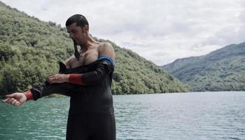 atleta di triathlon che si prepara per l'allenamento di nuoto sul lago foto