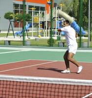 il giovane gioca a tennis all'aperto foto