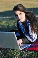 giovane ragazza adolescente lavora sul computer portatile all'aperto foto