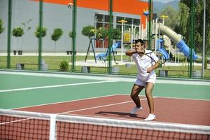 il giovane gioca a tennis all'aperto foto