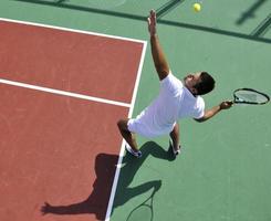 il giovane gioca a tennis all'aperto foto