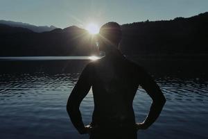 atleta di triathlon che inizia l'allenamento di nuoto sul lago foto