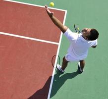 il giovane gioca a tennis all'aperto foto