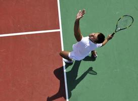 il giovane gioca a tennis all'aperto foto