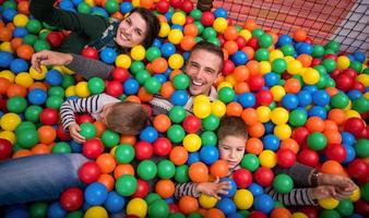 genitori e bambini giocando nel il piscina con colorato palle foto